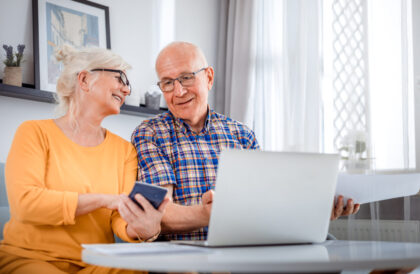 Senior couple checking bills using laptop at home