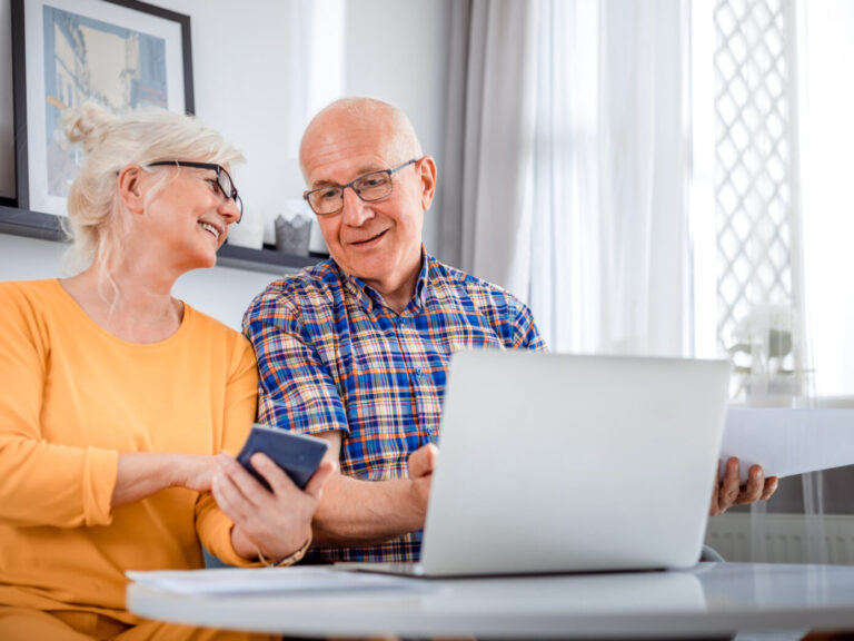 Senior couple checking bills using laptop at home